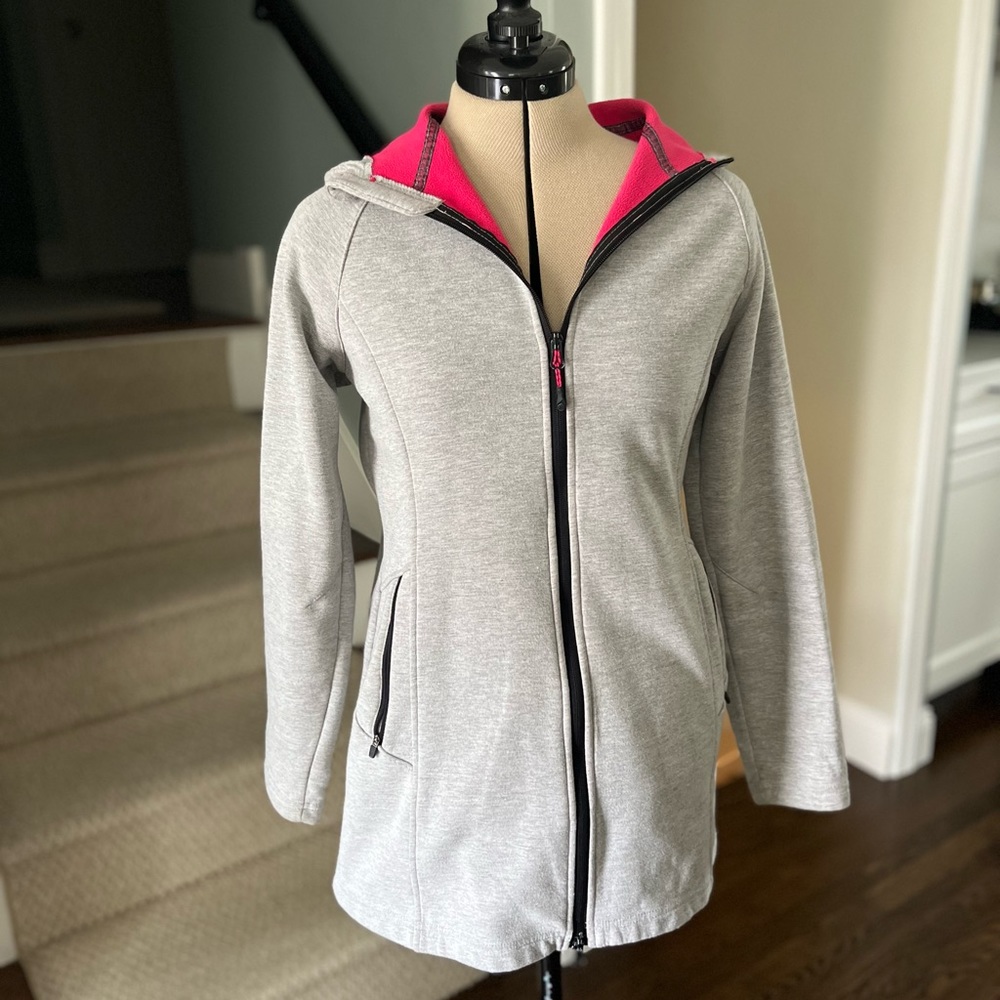 A light grey hooded coat with hot pink fleece lining. It’s in good condition.